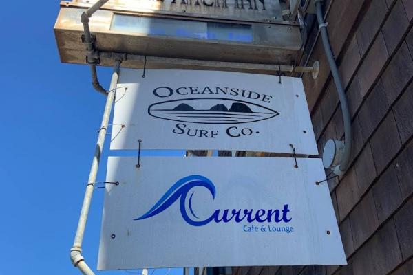 A sign for Three Arch Inn, Oceanside Surf Co., and Current Cafe In Oceanside OR