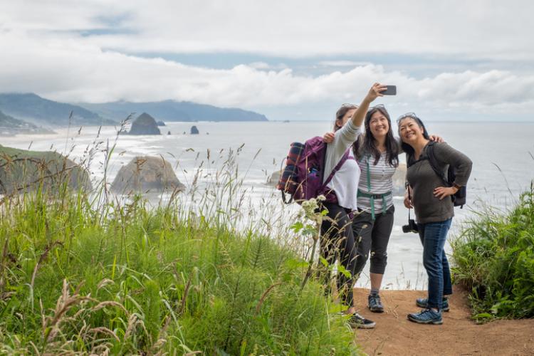 Three people taking a selfie at a scenic overlook on the oregon coast