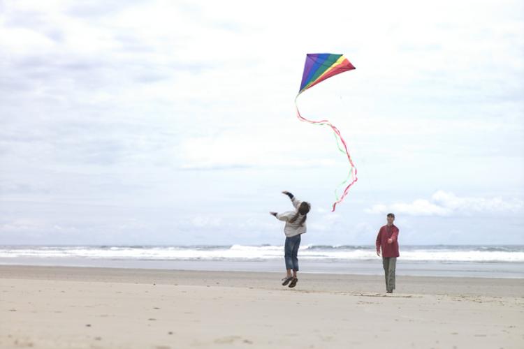 A parent and child flying a kite on an Oregon beach