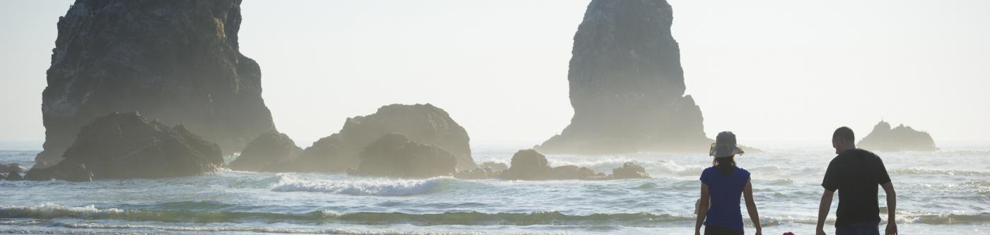 A family holds hands while looking out onto the ocean on an oregon beach